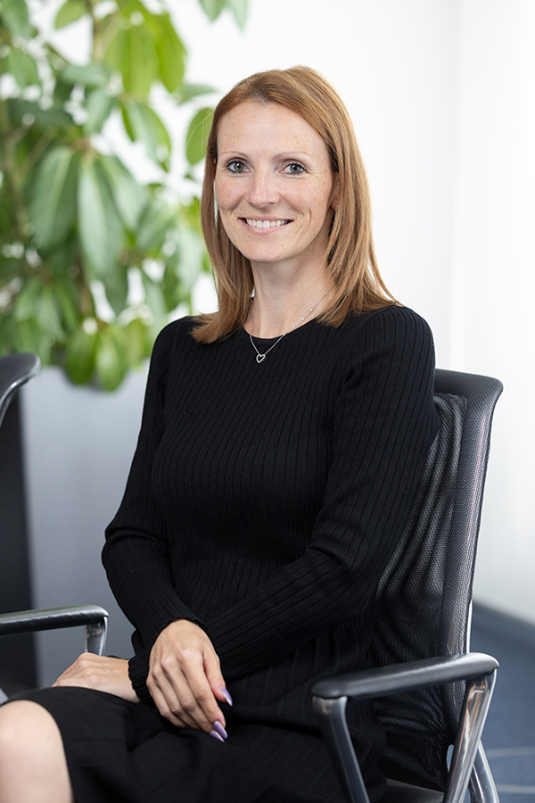 Lohnberatung bei der MIZ. Frau sitzt auf einem Stuhl und lächelt in die Kamera.