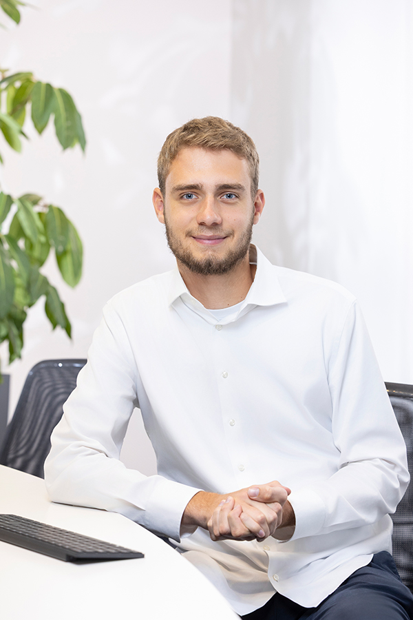 Werkstudent bei MIZ. Ein Mann in weißem Hemd sitzt lächelnd am Schreibtisch.