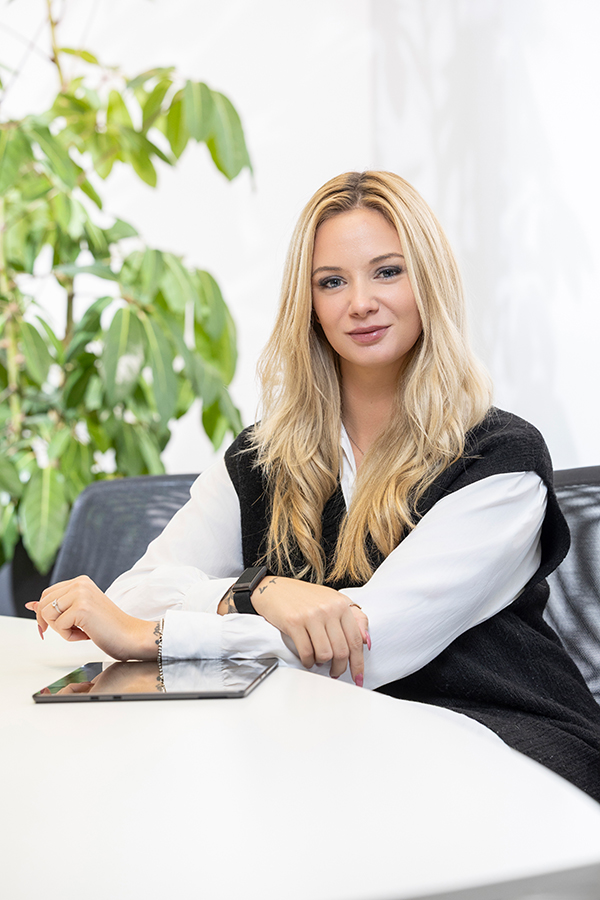 Zentrale-Services der MIZ. Frau sitzt an einem Tisch mit einem Tablet.